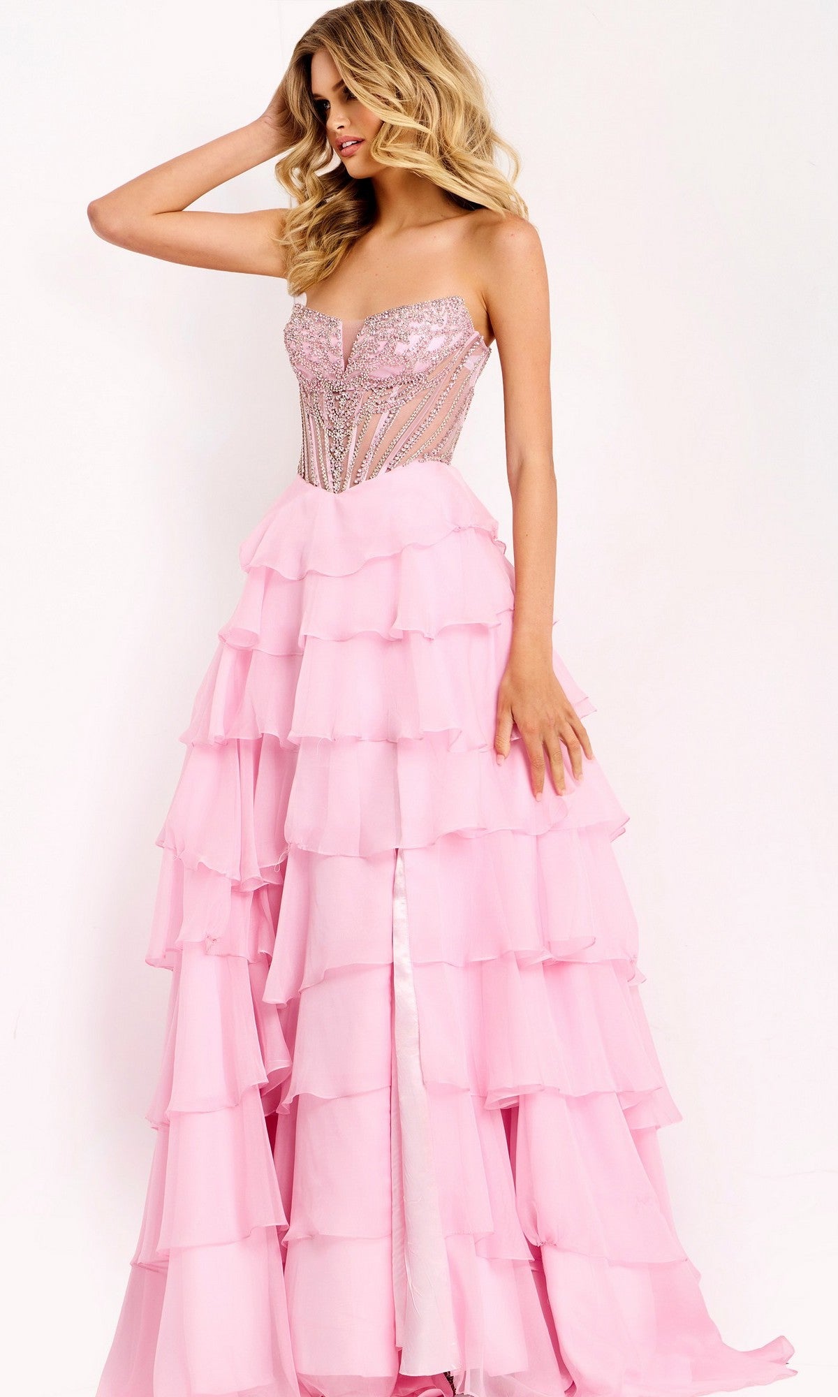 A woman poses against a plain background in the Jovani 49109 long prom dress, which features a strapless beaded corset bodice and a layered chiffon skirt.